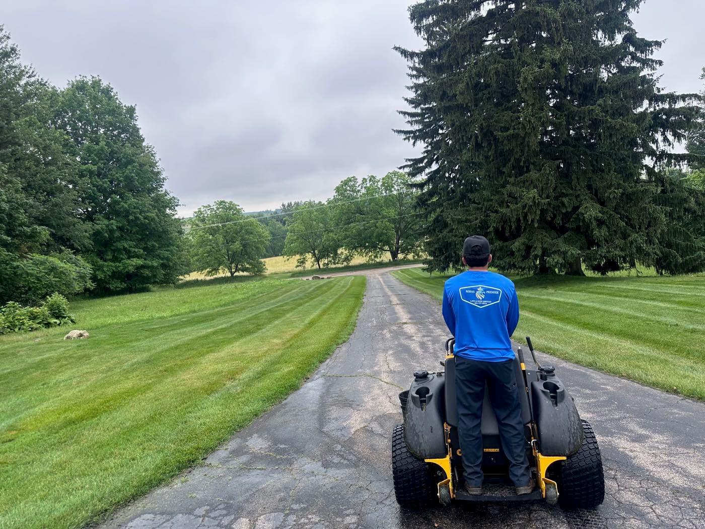 Rodas Premier crew member mowing crisp stripes into a large lawn